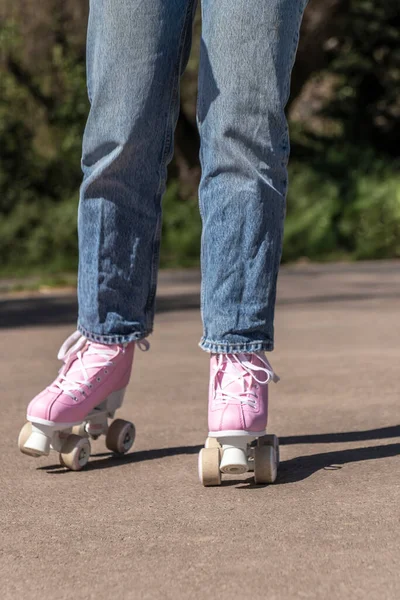 Kadın, kot pantolon ve pembe patenlerle kayıyor.