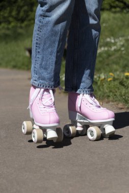 Kadın, kot pantolon ve pembe patenlerle kayıyor.