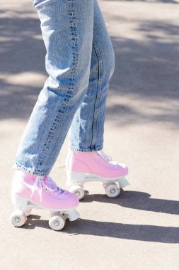 Kot pantolonlu kadın bacakları ve parkta pembe patenler.