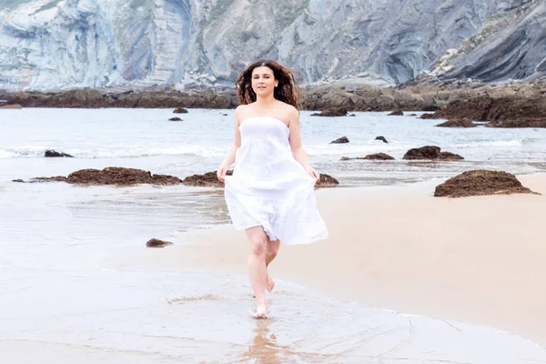 ビーチに沿って実行されている白いドレスのブルネットの女性幸せな — ストック写真