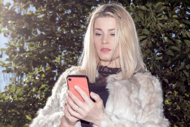 Parkta kırmızı bir arabaya bakan, beyaz önlüklü sarışın bir kadın.