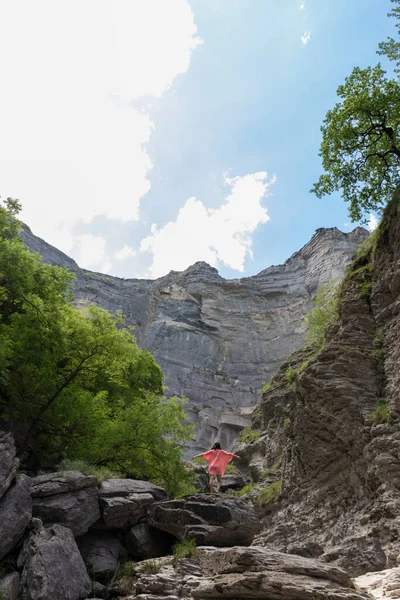 岩の山の上で腕を上げるシャツを着た美しい女性 — ストック写真
