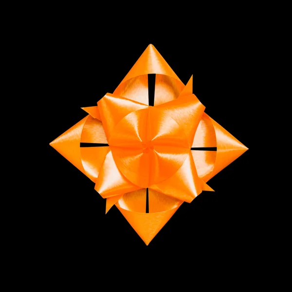 Flor de cinta naranja hecha con las manos dobladas sobre fondo negro — Foto de Stock