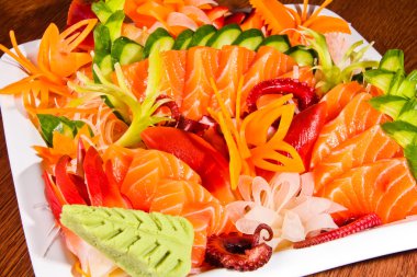 ahşap masa üzerinde beyaz tabak içinde karışık sashimi