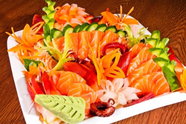 ahşap masa üzerinde beyaz tabak içinde karışık sashimi
