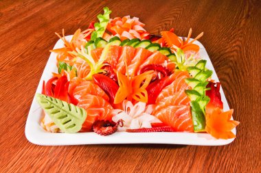 ahşap masa üzerinde beyaz tabak içinde karışık sashimi