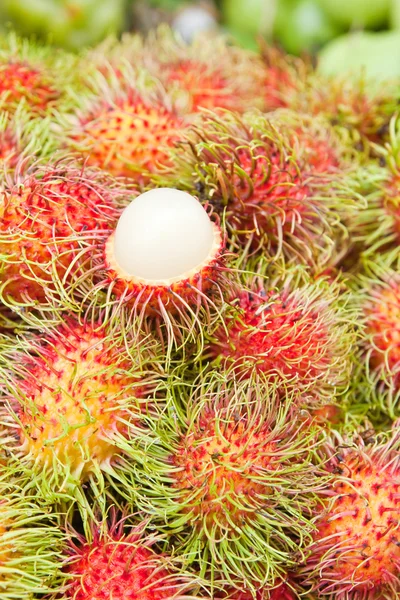 Owoce tropikalne, biały miąższ rambutan wśród czerwonych Jagodzian rambutan. — Zdjęcie stockowe