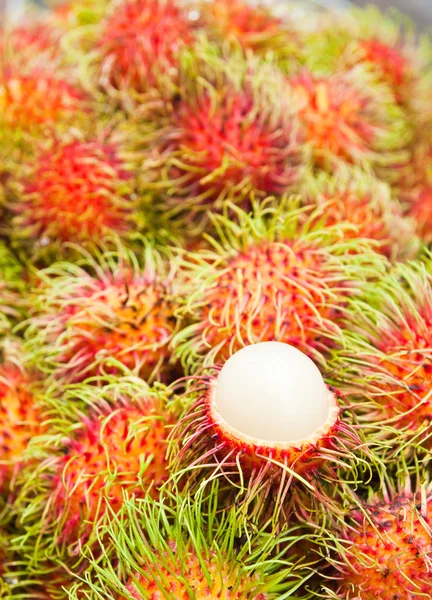 Tropisk frukt, vit massa rambutan bland röda rambutan. — Stockfoto