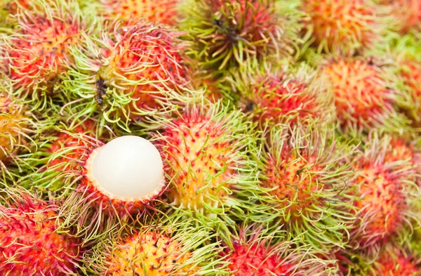 Tropisk frukt, vit massa rambutan bland röda rambutan. — Stockfoto