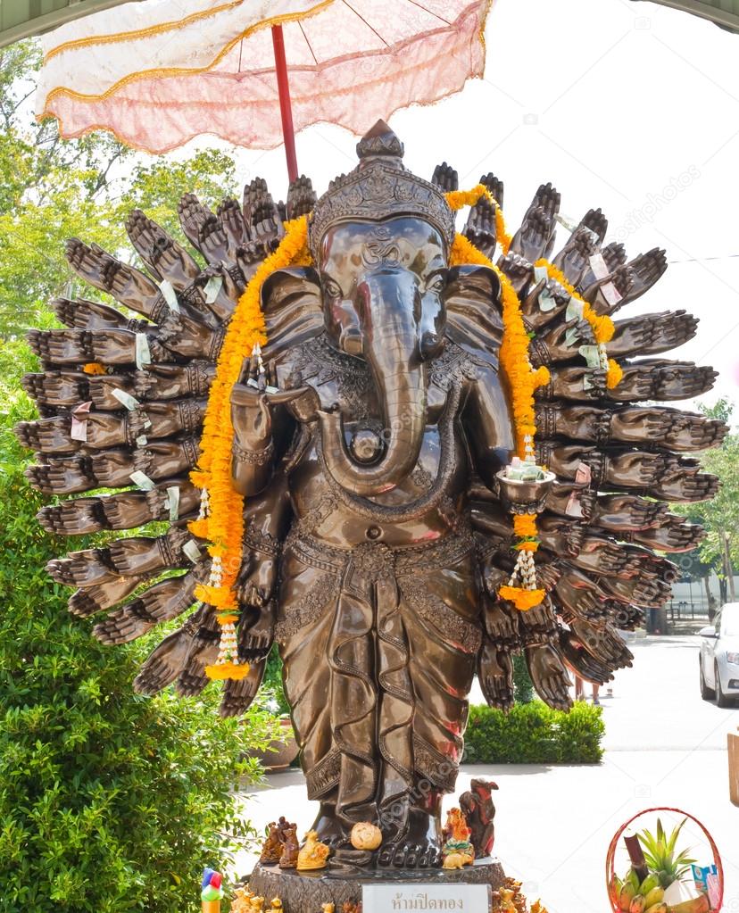 Many cast bronze hands of god Ganesha with yellow garland.