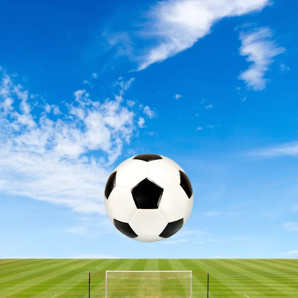 Pelota de fútbol con campo de fútbol contra fondo azul cielo — Foto de Stock