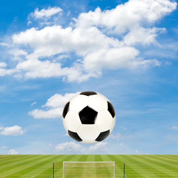 Футбольный мяч с футбольным полем на фоне голубого неба — стоковое фото