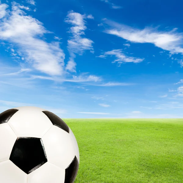 Pelota de fútbol con campo de hierba verde contra el cielo azul — Foto de Stock