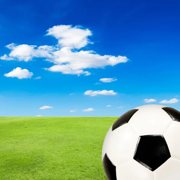 Pallone da calcio con campo di erba verde contro il cielo blu — Foto Stock