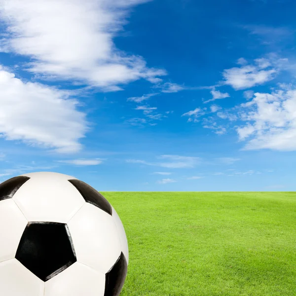 Pallone da calcio con campo di erba verde contro il cielo blu — Foto Stock