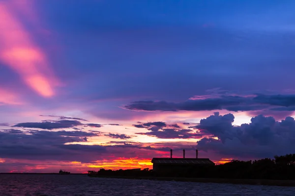 Usine au bord de la mer avec coucher de soleil coloré — Photo