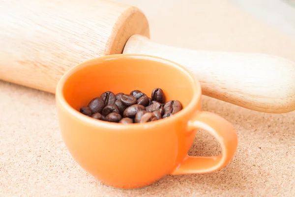 Tasse geröstete Kaffeebohnen und Rolle auf Korkhintergrund — Stockfoto