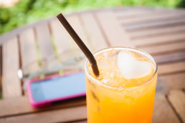 Heart cube ice in fresh orange juice with straw — Stock Photo, Image
