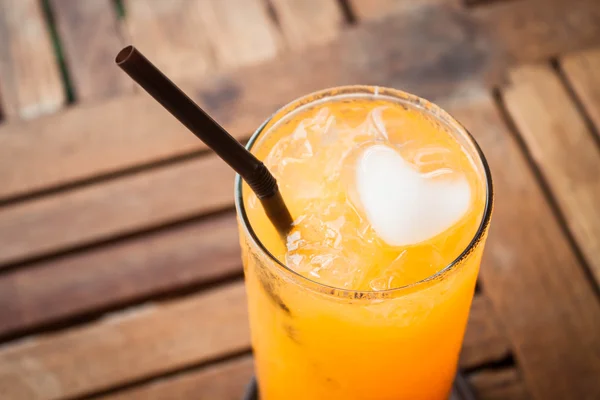 Close up orange juice with heart ice cube — Stock Photo, Image