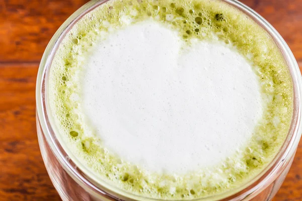 Cerrar té verde matcha caliente con leche en la mesa de madera —  Fotos de Stock