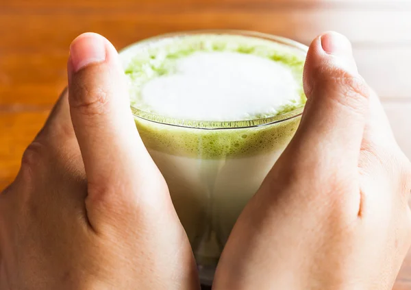 Hands hold hot drink of matcha green tea latte — Stock Photo, Image