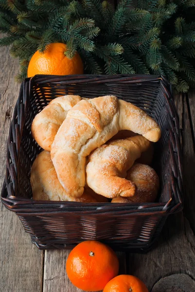 Croissants en una cesta oscura con mandarinas y abeto —  Fotos de Stock