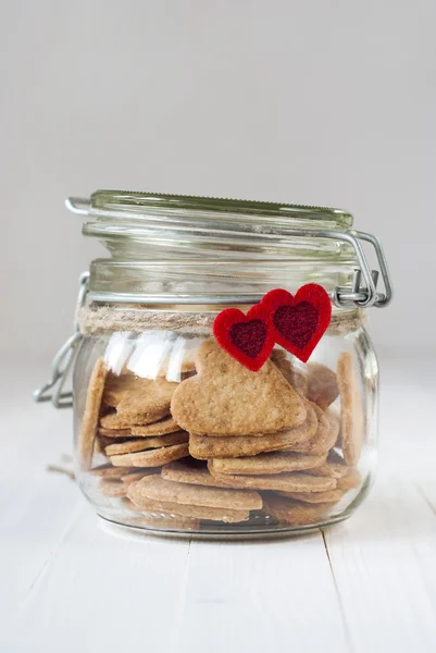 Ljus cookies i burken dekorerad med två röda hjärtan — Stockfoto
