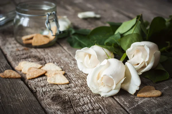 Tres rosas blancas y pastelería en la mesa de madera — Foto de Stock