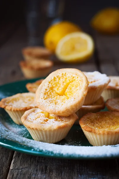 Yeşil plaka, ahşap arka plan grup limon tartlets — Stok fotoğraf