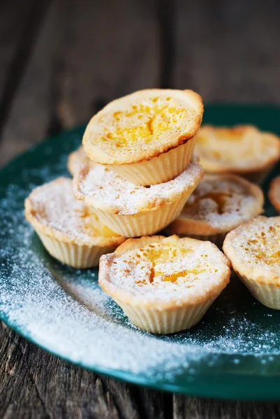 Lemon Tartlets with Powdered sugar on a green plate, wooden back — Stock Photo, Image