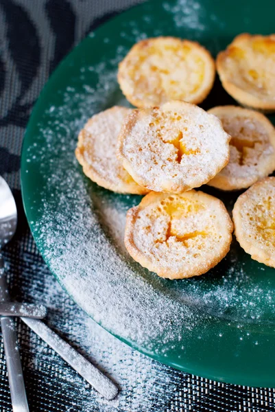 Tartaletas de limón con azúcar en polvo en un plato verde —  Fotos de Stock