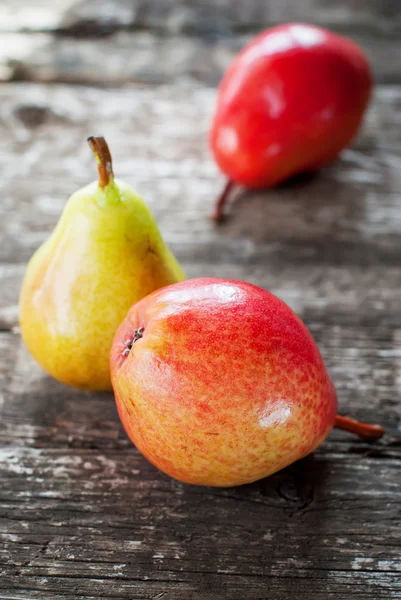 Koostumus kolme punaista päärynää puupöydällä — kuvapankkivalokuva