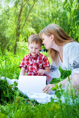 Anne ve oğlu bir yaz günü, kitap okuyarak park