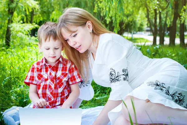 Mãe e Filho lendo um livro em um parque — Fotografia de Stock