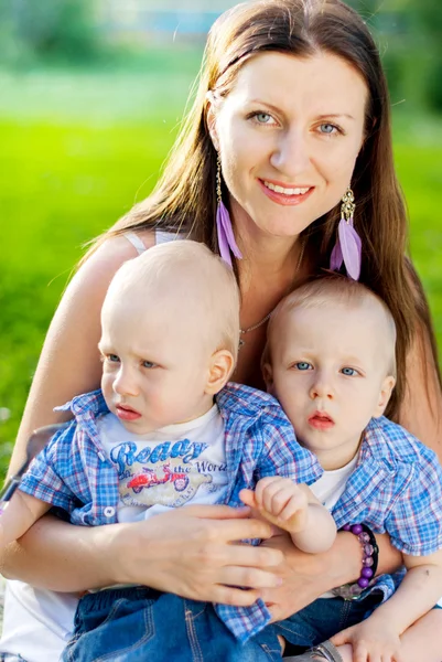 Gelukkige familie, jonge moeder met haar tweeling zonen plezier op de — Stockfoto