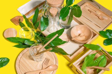 Sıfır atık. Organik ahşap mutfak yemekleri, aksesuarlar, doğal yapraklar, bambu kamışları. Parlak sarı arka planda sağlıklı ekolojik ürünler