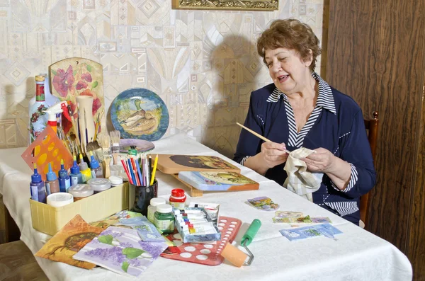 Gelukkig oudere vrouw - kunstenaar maakt decoupage — Stockfoto