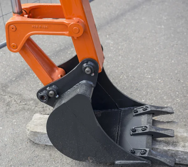 Cubo de la excavadora de pie sobre el asfalto —  Fotos de Stock