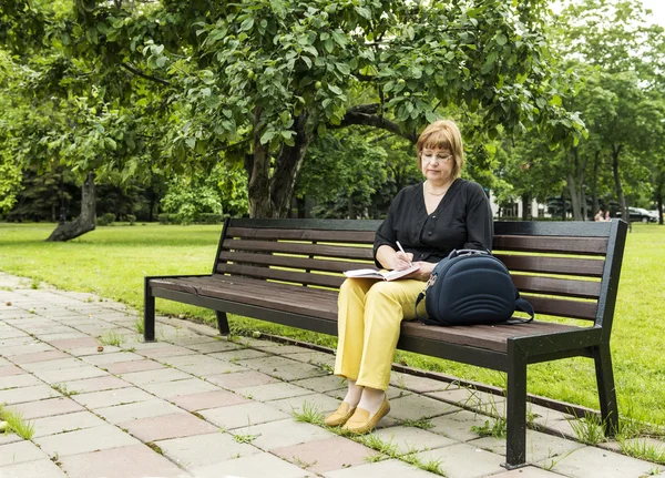 Donna prevede di lavorare ammaccatura seduto nel parco in una pausa pranzo — Foto Stock