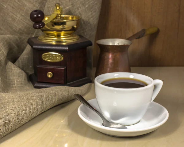 Kaffee in einer Tasse auf einem Marmortisch, Handmühle und Cezve — Stockfoto