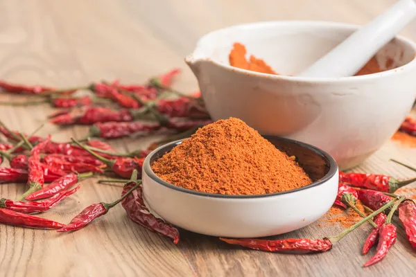 Chile rojo picante en polvo en un mortero y vainas — Foto de Stock