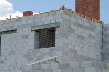 Beyaz köpük bloklardan yapılmış inşaat halindeki bir evin inşaatı. Yeni ev çerçevesi oluşturuluyor.