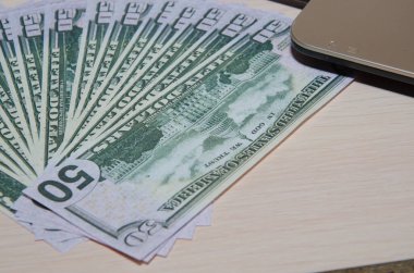 Diz üstü bilgisayar ve Amerikan doları, bilgisayar defteri ve dolar banknotları tahtadan bir arka planda, Amerikan doları banknotlu teknoloji,