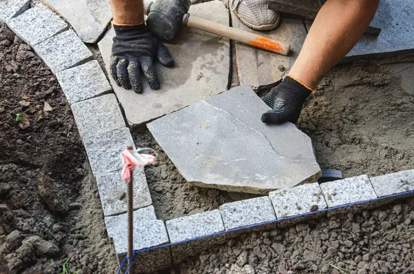 Evin yakınında asfalt inşaatı. Tuğlacı beton kaldırım taşlarını inşa etmek için yerleştirdi