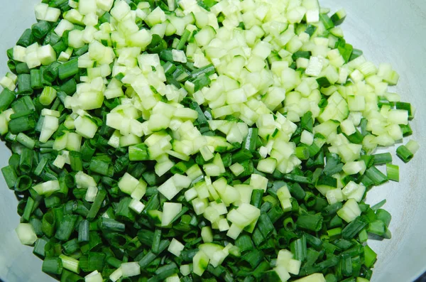 Bambu kesme tahtasında organik çekirdeksiz bir salatalığı ince ince doğramak.