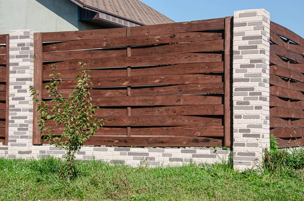 Dekorativ betong staket med tegelstolpar nära ett bostadshus med en trädgård. — Stockfoto