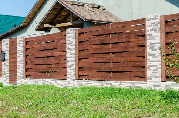 Dekorativ betong staket med tegelstolpar nära ett bostadshus med en trädgård. — Stockfoto