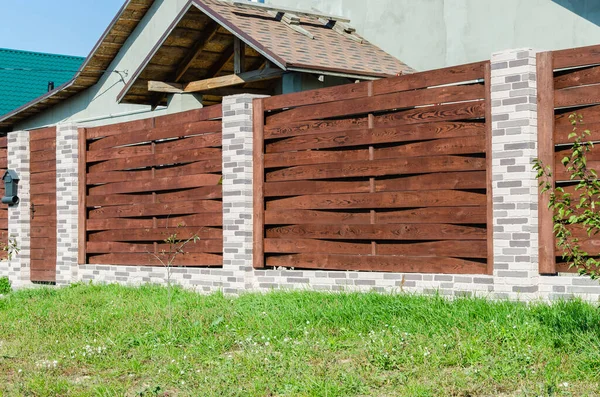Bahçeli bir konut binasının yanında tuğla direkli dekoratif beton çitler..