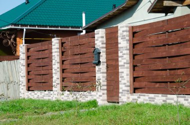 Bahçeli bir apartmanın yanında tuğla direkli dekoratif turuncu çit..