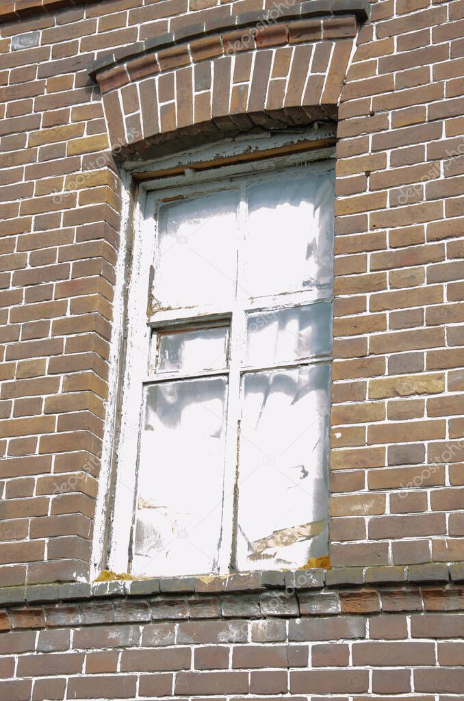 old, tumbledown christian window surrounding red brick edges.